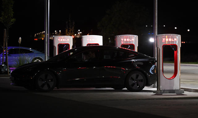 Ein Tesla lädt nachts an einer Ladestation.
