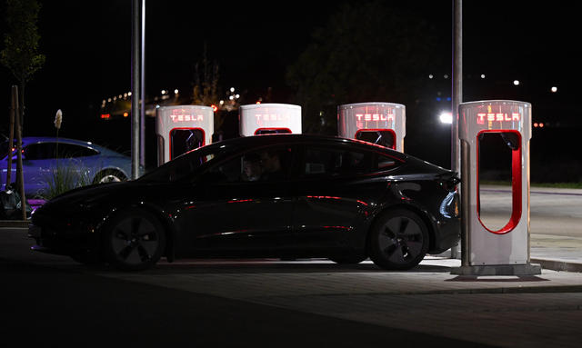 Tesla an Ladestation Ein Tesla lädt nachts an einer Ladestation.