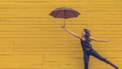 Frau mit Schirm vor gelber Wand