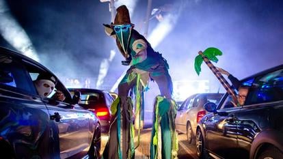 Ein Akteur geht während einer Auto-Disco auf Stelzen über den Parkplatz der Diskothek „Index“. 
