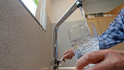 Ein Mann befüllt ein Glas mit Leitungswasser aus dem Wasserhahn