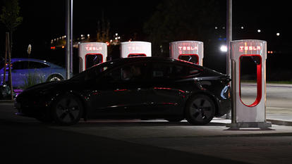 Ein Tesla lädt nachts an einer Ladestation.