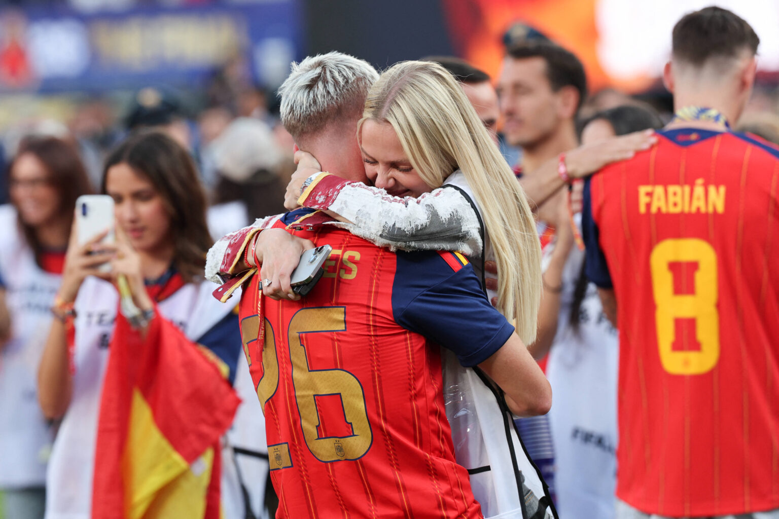 Dani Olmo und seine Freundin Laura Abla feiern gemeinsam mit dem WM-Pokal auf dem Spielfeld