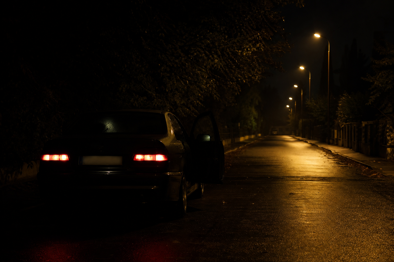 Auto mit leicht geöffneter Tür in einer dunklen Wohnstraße bei Nacht