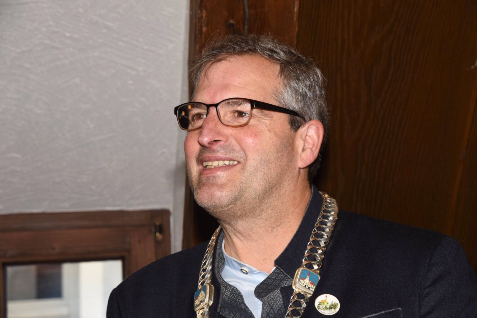 Christian Bauer, Bürgermeister von Grafing, lächelnd mit Amtskette im Rathaus