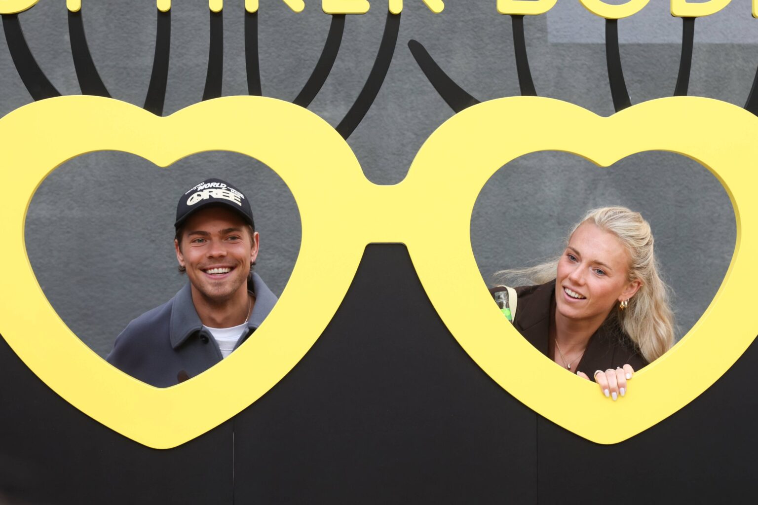 Emily Kerner und ihr Ehemann Jendrik Sielaff blicken durch eine herzförmige Fotowand bei einer Party in Hamburg