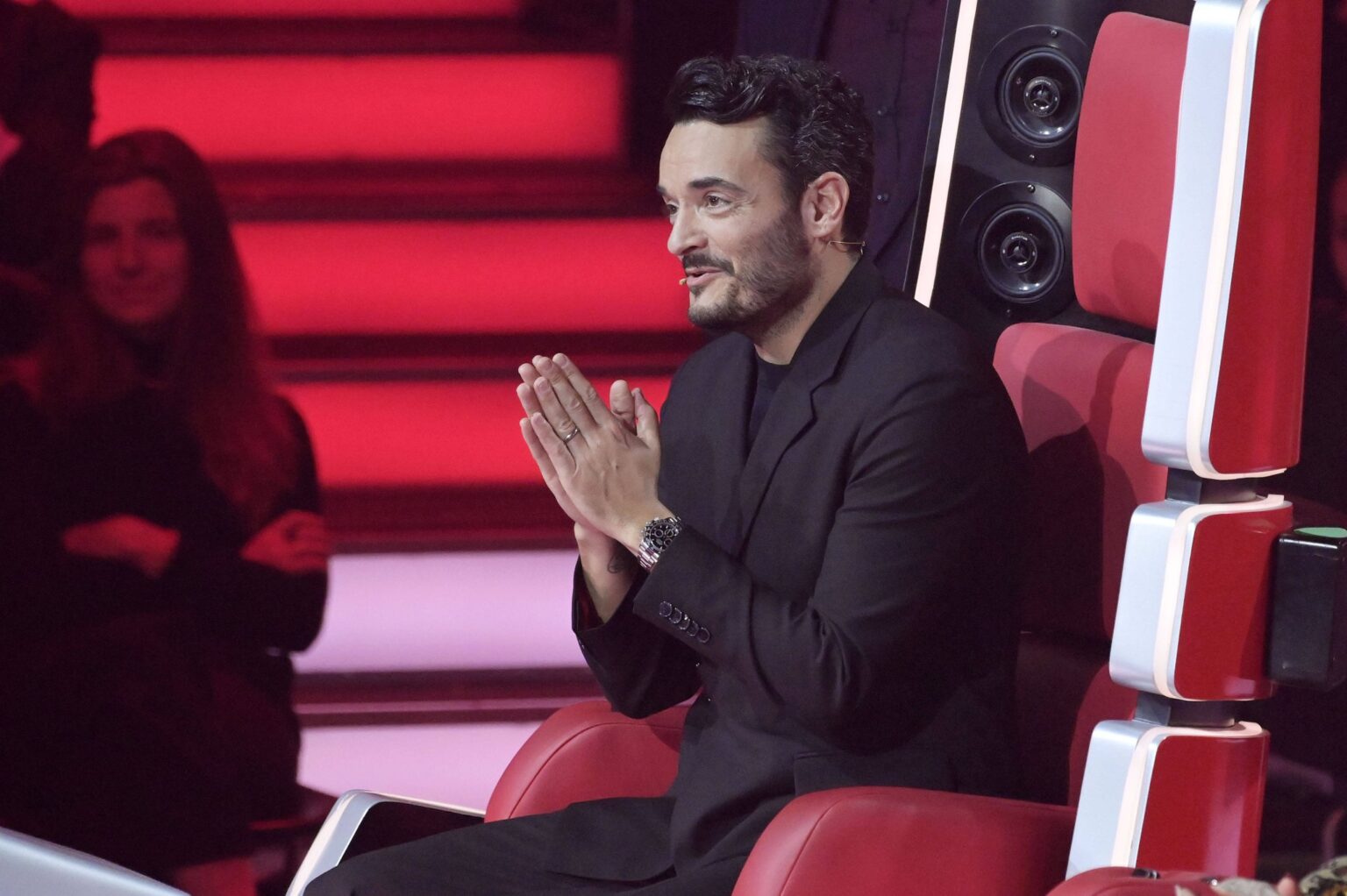 Giovanni Zarrella sitzt mit gefalteten Händen auf dem roten Coach-Stuhl von „The Voice of Germany“