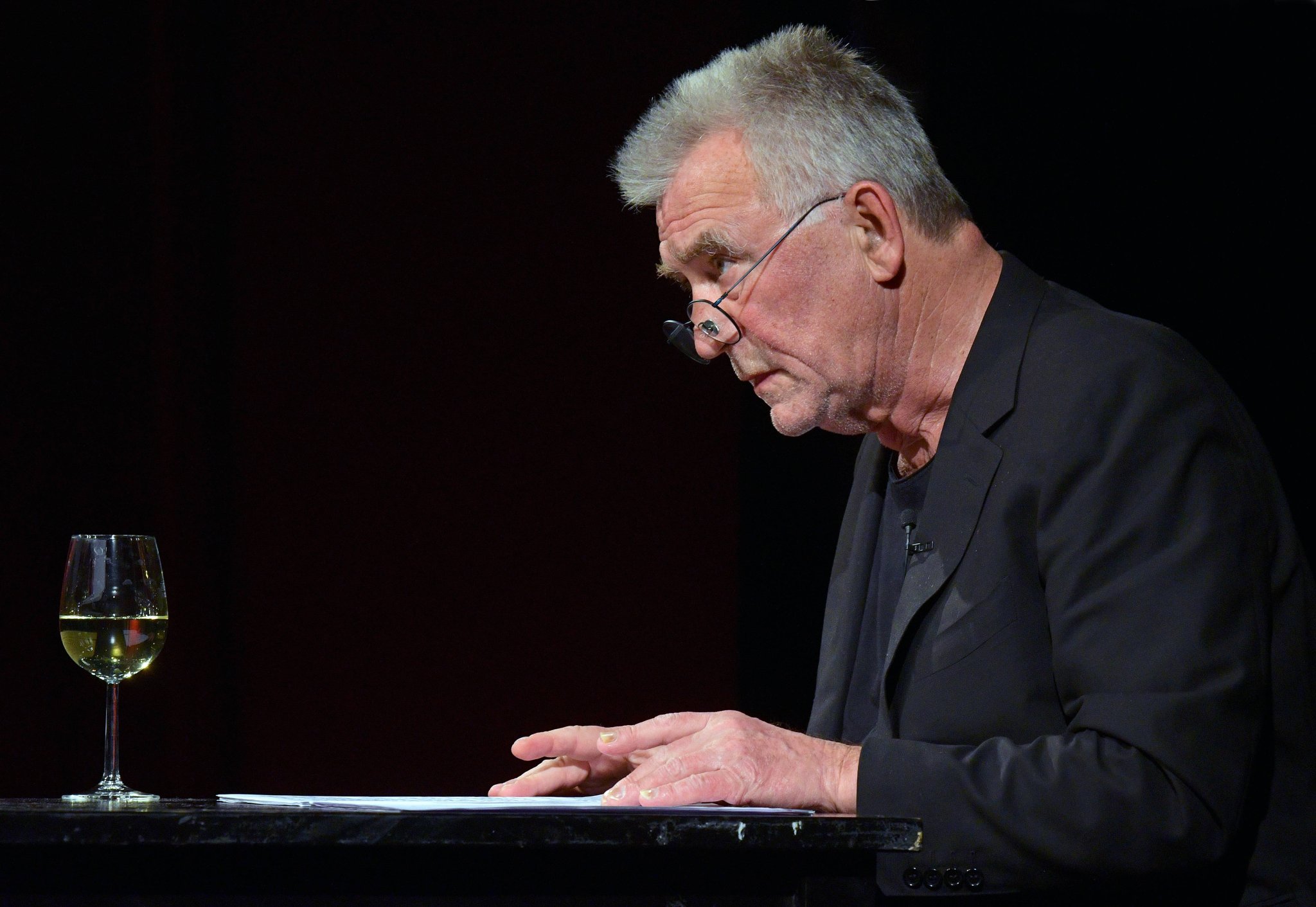 Schauspieler Heinz Marecek liest an einem Tisch auf der Bühne des Stadttheaters Gmunden