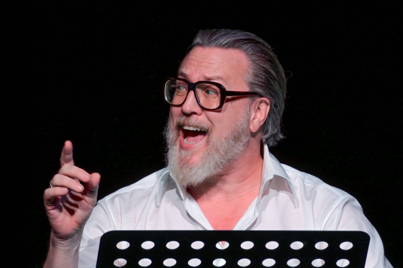 Nicholas Ofczarek mit Brille am Lesepult auf der Bühne