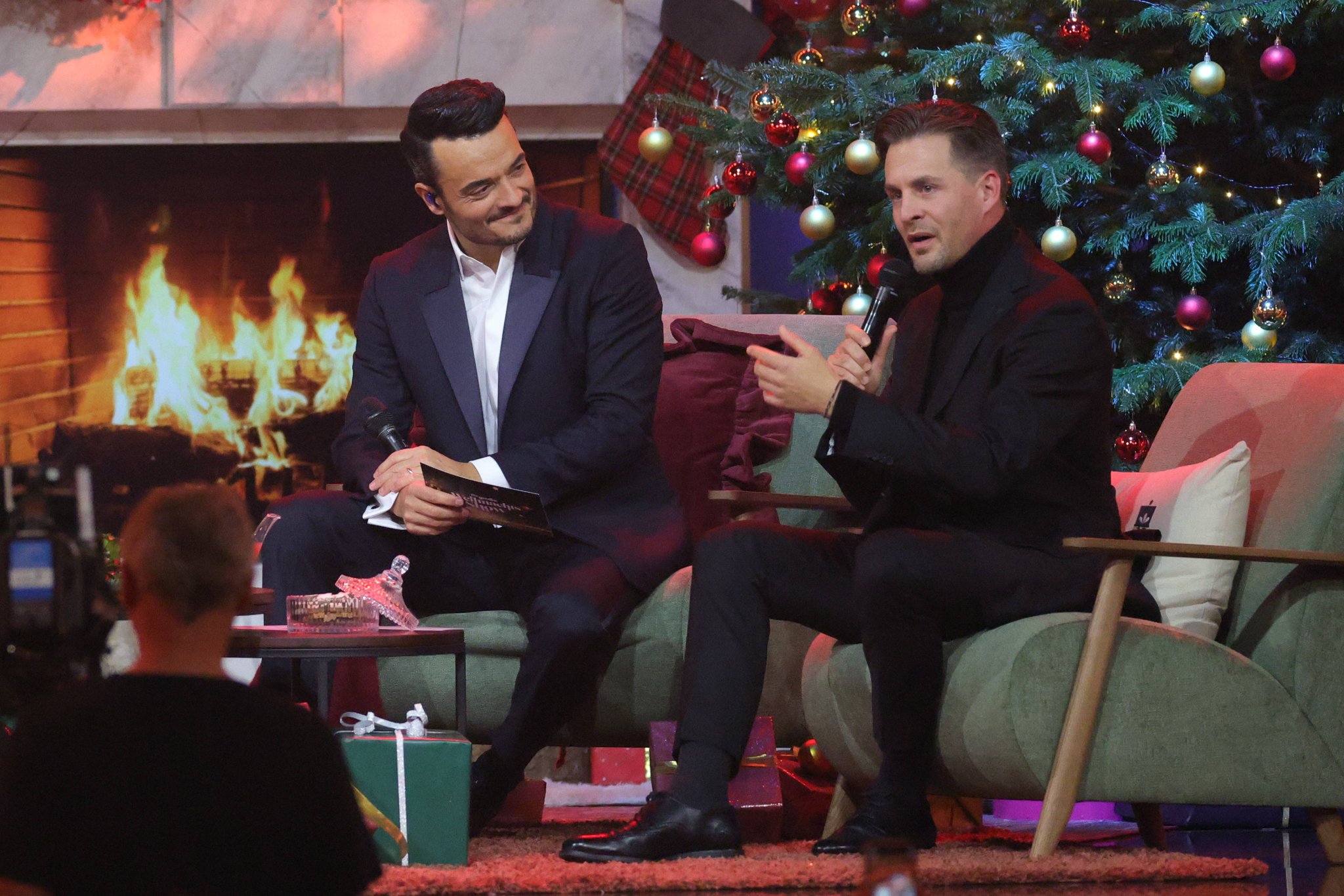 Giovanni Zarrella und Alexander Klaws sitzen vor einem Kaminfeuer auf einer Couch