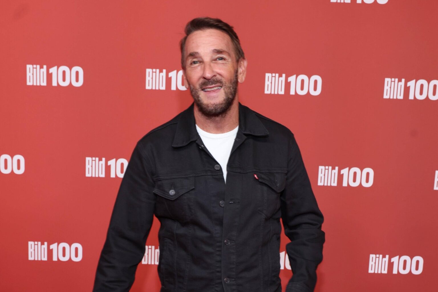 Bergdoktor-Star Mark Keller lächelt auf dem roten Teppich bei BILD100 in Berlin