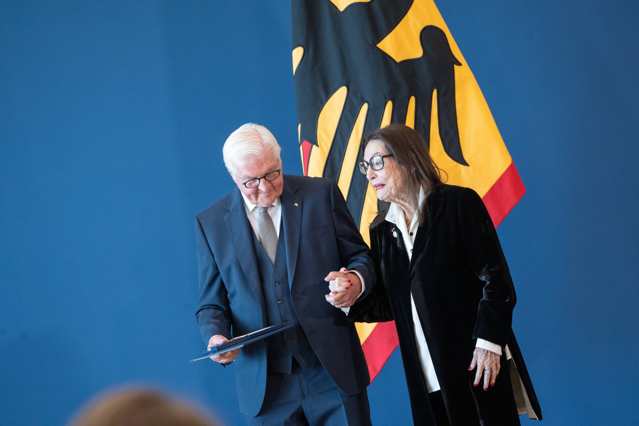 Bundespräsident Frank-Walter Steinmeier hält Nana Mouskouri bei der Ordensverleihung in Berlin an der Hand