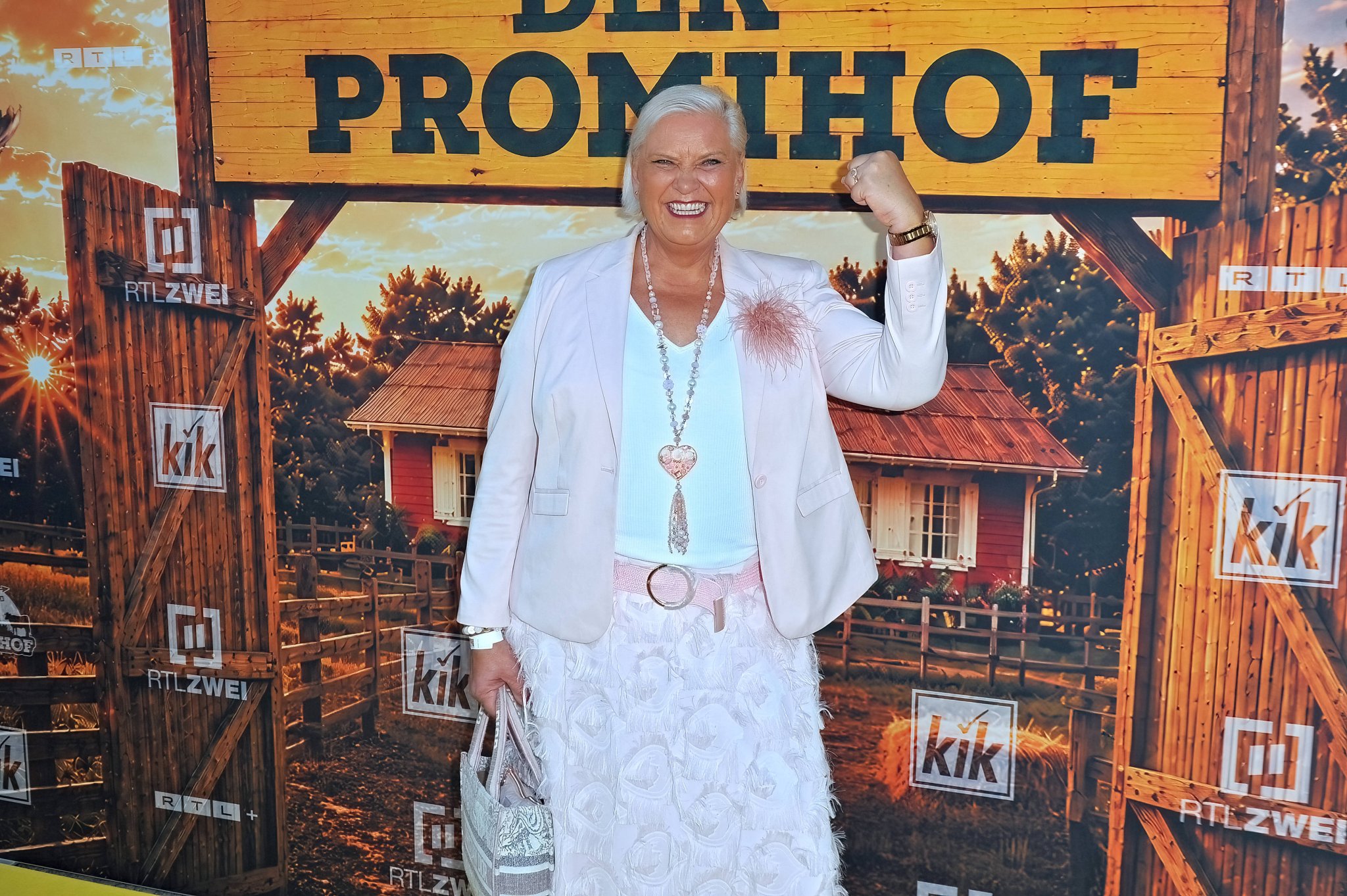 Meike Buschening-Kaffenberger vor dem Logo von „Der Promihof“ bei der Premierenfeier in Hürth